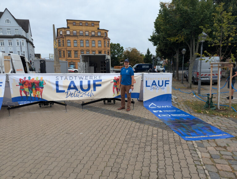 Aufbau für den Stadtwerkelauf am Roßplatz Absperrgitter mit Bannern des Stadtwerkelaufs vor der aufgebauten Bühne am Roßplatz in Delitzsch