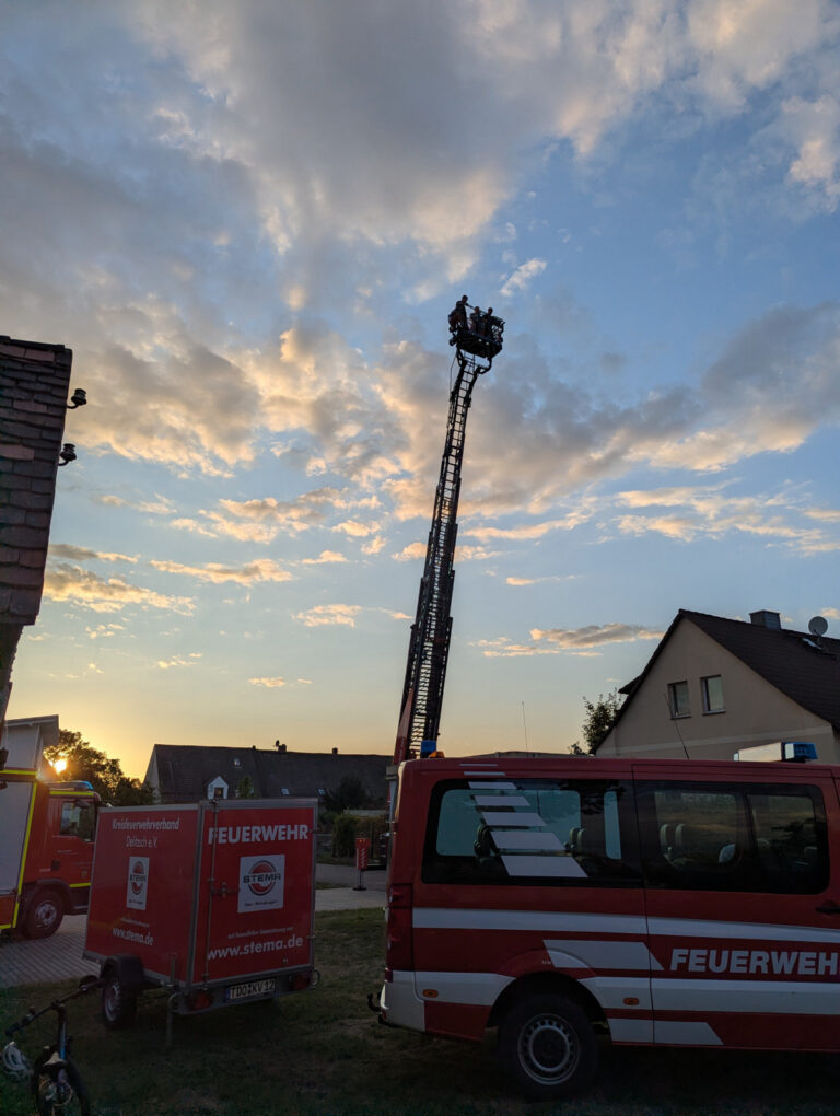 Drehleiter beim Feuerwehr-Vereinsfest Benndorf Die Drehleiter der Feuerwehr Delitzsch ist bei Sonnenuntergang am Gerätehaus Benndorf ausgefahren; mehrere Menschen stehen im Korb.