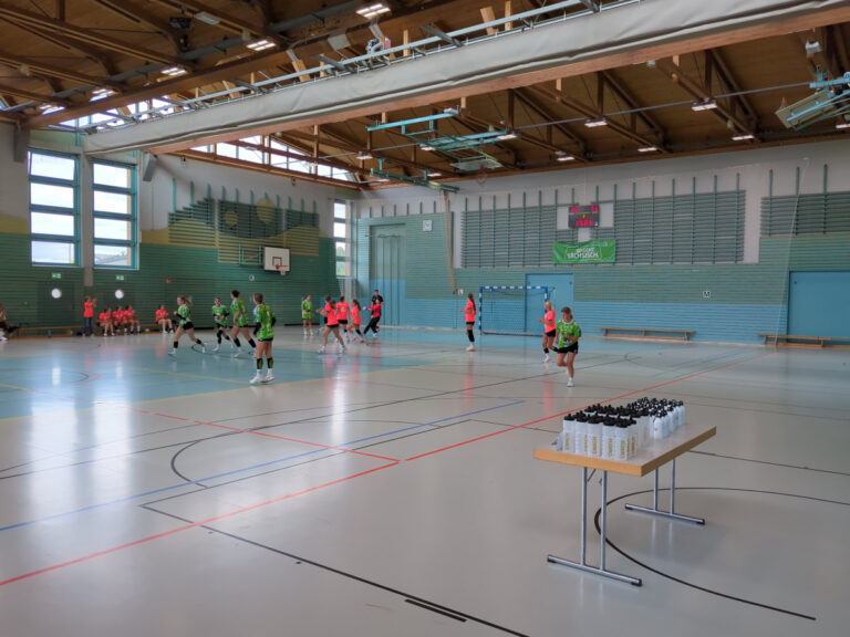 Spielerinnen der SG Kühnau und des HV Glesien im entscheidenden letzten Spiel des Lober-Cups; im Vordergrund steht ein Tisch mit Pokalen.