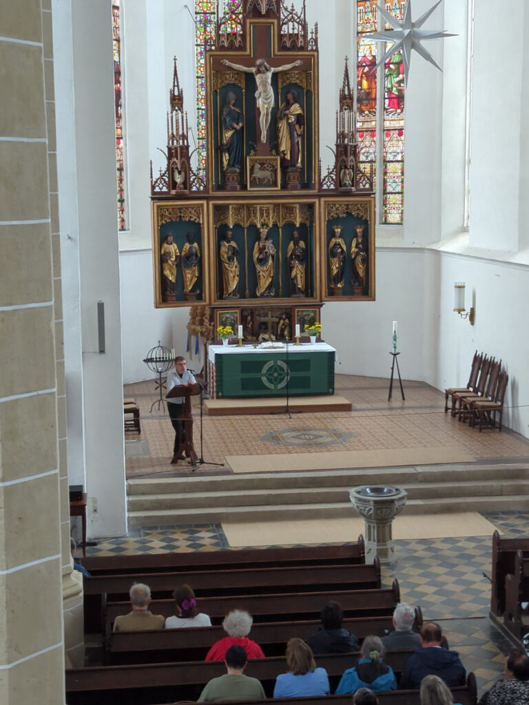 Kantor Jörg Topfstedt erläutert vor dem Altar der Delitzscher Stadtkirche das Programm von OrgelPunkt12.