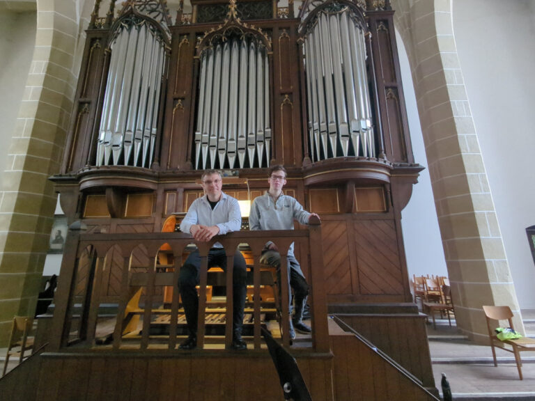 Kantor Jörg Topfstedt und Orgelstudent Niklas Müller stehen vor der Rühlmann-Orgel der Stadtkirche St. Peter und Paul in Delitzsch.