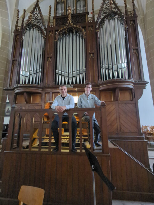 Kantor Jörg Topfstedt und Orgelstudent Niklas Müller stehen vor der Rühlmann-Orgel der Stadtkirche St. Peter und Paul in Delitzsch.