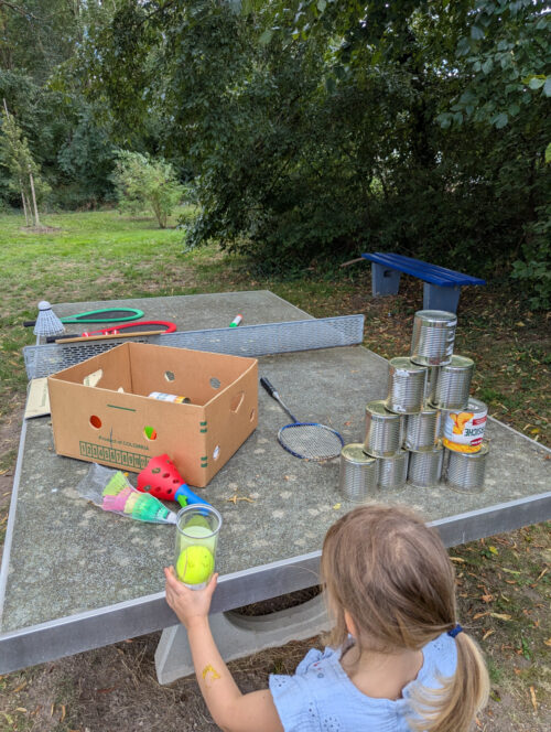 Ein Kind steht vor einer Tischtennisplatte mit Dosen, Ball und weiteren Spielgeräten beim Storkwitzer Jubiläumsfest.