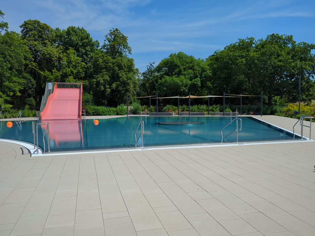 Blick auf die Freibadanlage des Elberitzbades mit Rutsche und Becken.