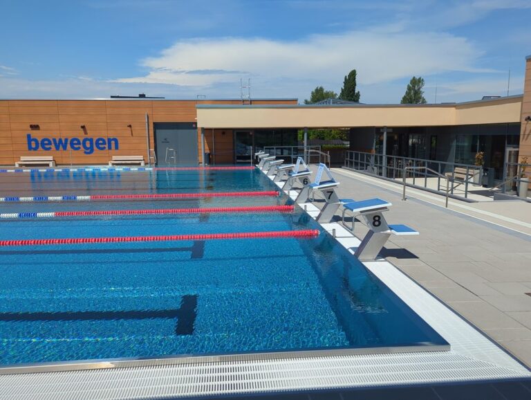 Blick über das Sportbecken des Elberitzbades mit Startblöcken und Funktionsgebäude.