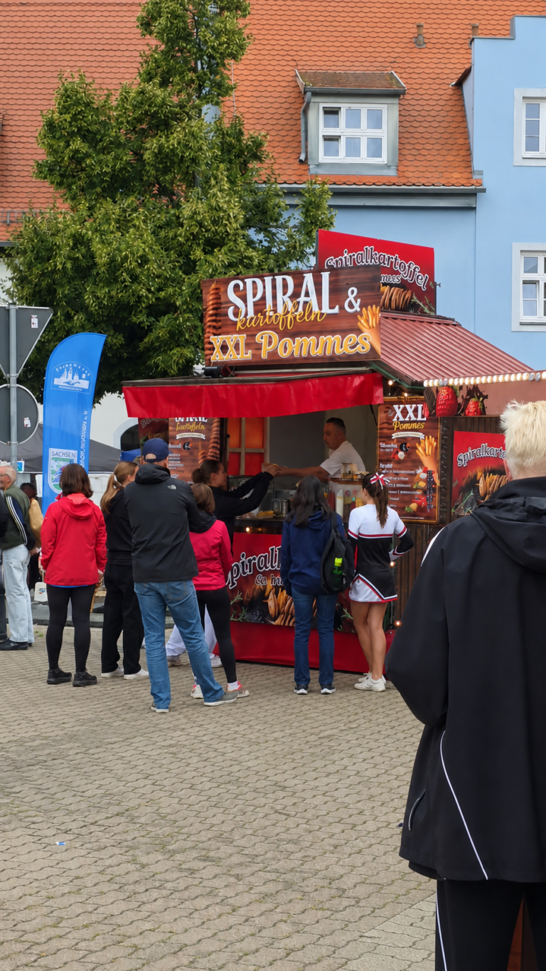 Besucherinnen und Besucher stehen an einem Imbisswagen im liebevoll genannten Roselly Food Court am Roßplatz