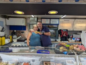 Eine Frau und ein Mann stehen hinter der Auslage von Neptuns Fischinsel beim Hallenflohmarkt in Delitzsch.