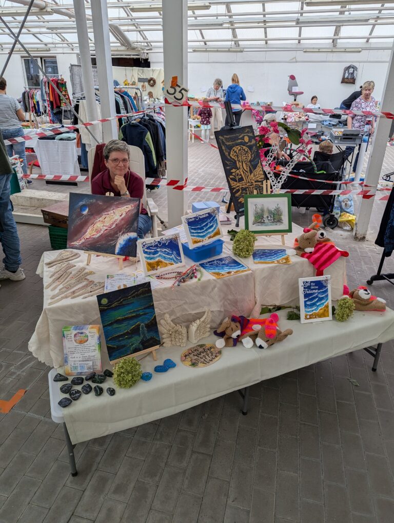 Ein Verkaufsstand mit Bildern, Spielzeug und Haushaltsgegenständen beim Hallenflohmarkt in Delitzsch.