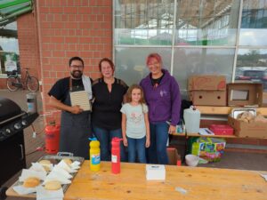 Drei Erwachsene und ein Kind stehen am Grillstand von SiTa’s vor der Flohmarkthalle in Delitzsch.