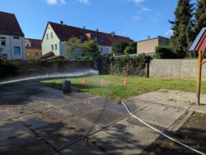 Ein Wasserstrahl läuft beim Schulfest über einen mit Leitkegeln markierten Übungsparcours der Feuerwehr Benndorf.