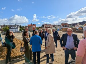 Politische, kommunale und am Bau beteiligte Gäste sprechen auf dem Baufeld der Artur-Becker-Oberschule miteinander.