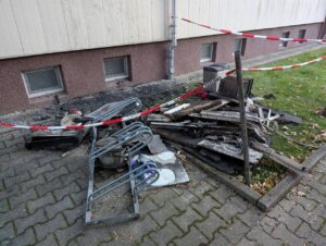Verbranntes Kücheninventar und weitere Gegenstände liegen hinter Absperrband neben einem Mehrfamilienhaus in Delitzsch.