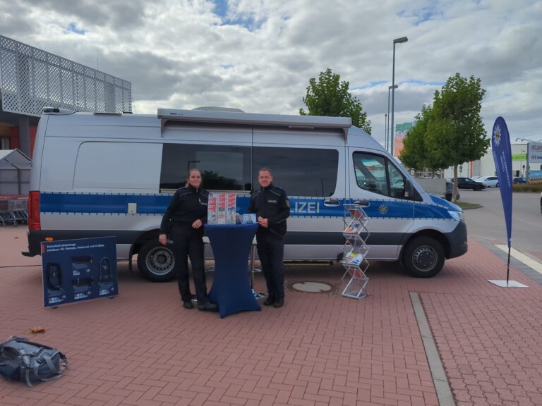 Zwei Polizeibeamte stehen vor dem Präventionsmobil in Delitzsch.